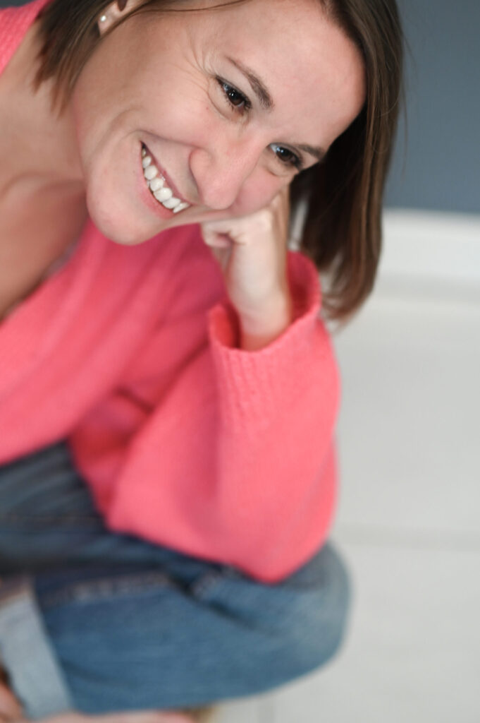 Portrait souriant d’une thérapeute en pull rose, séance photo AuraLia